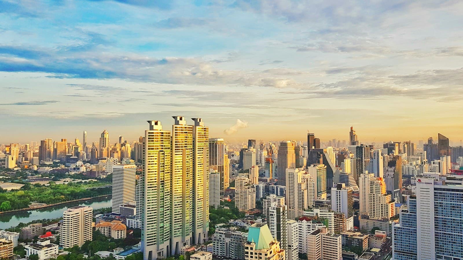 Bangkok high-rise skyline glowing at sunrise beside a green park